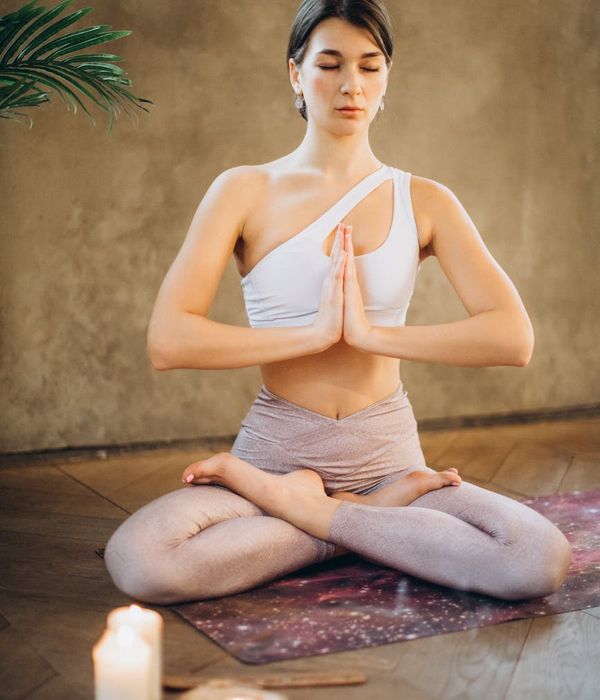 Woman in a peaceful lotus yoga pose on a mat, meditating indoors.